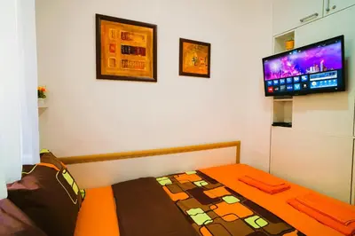 a small bedroom with a bed and a flat screen tv at Golden Place Belgrade in Belgrade