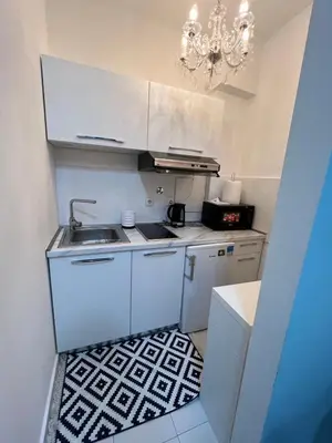 a small kitchen with white cabinets and a chandelier at Sandra City Center Apartment in Belgrade