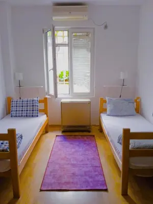 two beds in a room with a window and a rug at Jasmin in Belgrade