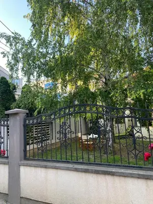 a black fence with a table and a tree at House Reko in Novi Grad