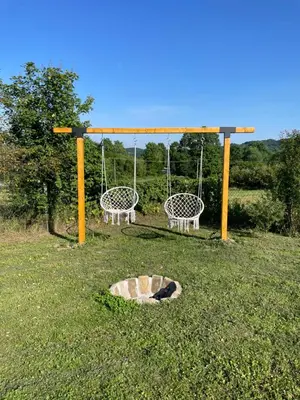 two swings and a fire pit in a field at Deda Momirov zavičaj in Tulež