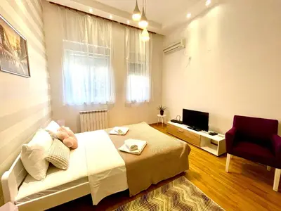 a bedroom with a bed and a chair and a television at DORA stan na dan Novi Beograd Savada Blok A, parking 5 evra dan in Belgrade