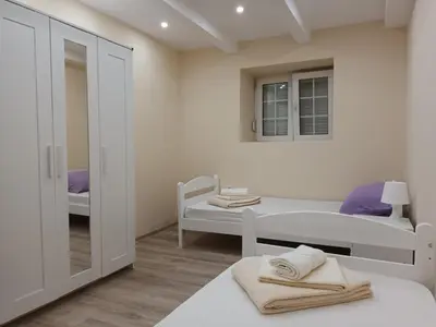 a white bedroom with a bed and a mirror at Apartman Marina in Sajmište