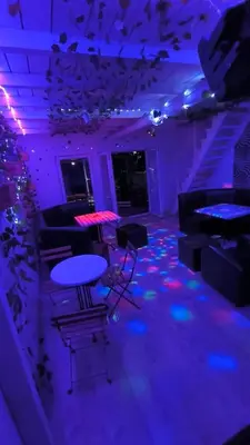 a room with purple lights and a table and chairs at cunami kucica sa bazenom in Belgrade