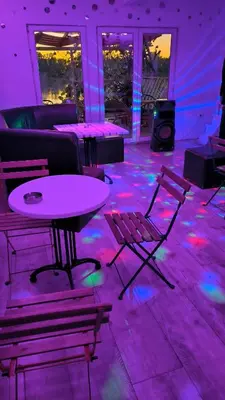 a room with a table and chairs and purple lights at cunami kucica sa bazenom in Belgrade