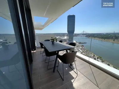 a table and chairs on a balcony with a view of a river at BW TERRACE top floor apartments with river view & self check-in in Belgrade