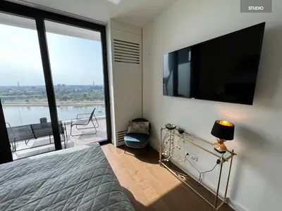 a bedroom with a flat screen tv and a bed at BW TERRACE top floor apartments with river view & self check-in in Belgrade