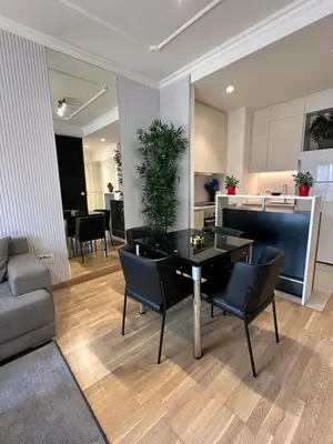 a living room with a table and chairs and a kitchen at Modern Apartment in Belgrade Waterfront in Belgrade