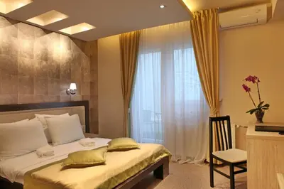 a bedroom with a bed with a window and a chair at Garni Hotel Vozarev in Belgrade