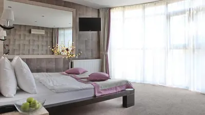 a bedroom with a bed with purple pillows and a television at Garni Hotel Vozarev in Belgrade