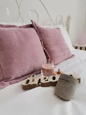 a bed with purple pillows and a candle and a candle holder at VIKONT studio apartment with parking 5 eur per day in Belgrade
