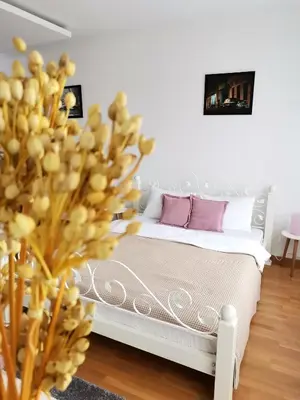 a bedroom with a white bed with purple pillows at VIKONT studio apartment with parking 5 eur per day in Belgrade