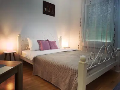 a bedroom with a white bed with pink pillows and a window at VIKONT studio apartment with parking 5 eur per day in Belgrade