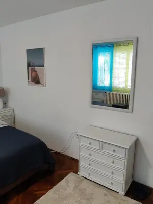 a bedroom with a bed and a dresser and a window at Apartment Miljakovac in Belgrade
