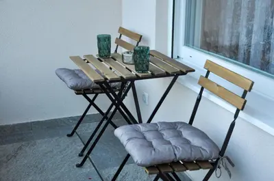 a wooden table with two chairs and a table with a window at Guest House Atena in Nova Pazova
