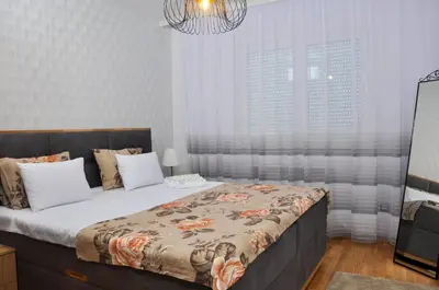 a bedroom with a large bed and a chandelier at Guest House Atena in Nova Pazova