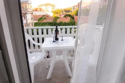 a white table with a bottle and glasses on a balcony at Apartman Janković in Arandjelovac