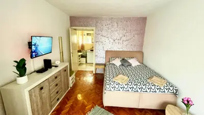 a bedroom with a bed and a dresser with a television at Sweet Venac in Belgrade