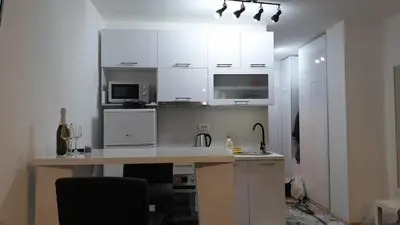 a kitchen with white cabinets and a desk in a room at Zorz in Belgrade