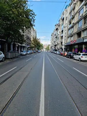 an empty city street with cars parked on the sides at The Blue Velvet Apartment in Belgrade