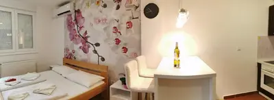 a small room with a bed and a bottle of wine on a table at Apartman Dana in Nova Pazova