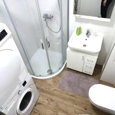 a bathroom with a shower and a sink and a washing machine at A BLOK1 NEW BELGRADE in Novi Beograd