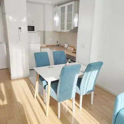 a kitchen with a white table and blue chairs at A BLOK1 NEW BELGRADE in Novi Beograd