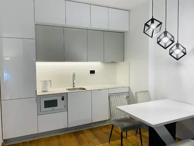a kitchen with white cabinets and a table with chairs at Oasis in Jajinci