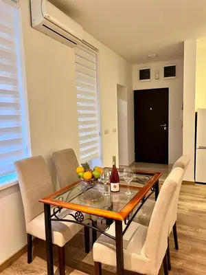 a dining room table with a bottle of wine and chairs at Hugolina LUX in Belgrade