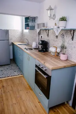 a kitchen with blue cabinets and a wooden counter top at Kućerak Sofija in Čortanovci