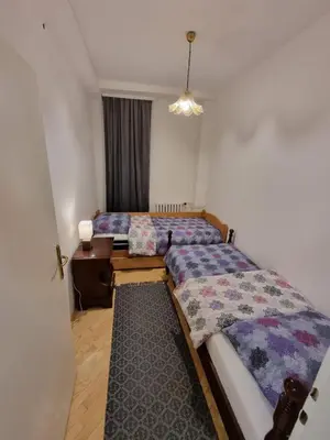 a bedroom with two beds and a table and a window at Big Downtown Apartment across National Theater (2 Bedrooms) in Belgrade