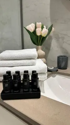 a bathroom with white towels and a vase of white flowers at DOM Boutique Apartments OLD TOWN in Belgrade