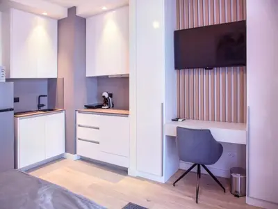 a small kitchen with white cabinets and a chair at BW Aurora 108 in Belgrade