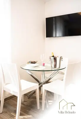 a glass table and two white chairs in a room at Belrado Apartments in Belgrade