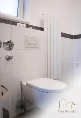 a white bathroom with a toilet and a sink at Belrado Apartments in Belgrade