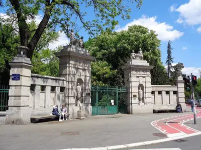 two people sitting on a bench in front of a fence at Apartman Valdano in Belgrade