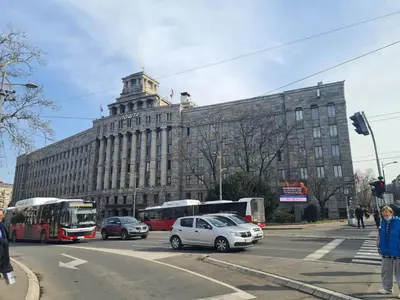 a large building with buses and cars on a street at Apartman Valdano in Belgrade
