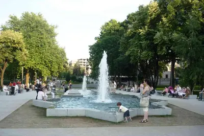 a group of people sitting around a fountain in a park at Apartman Valdano in Belgrade