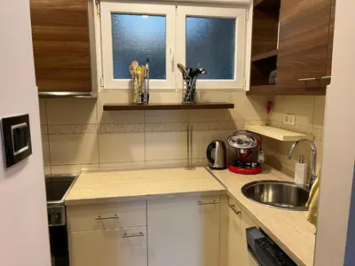 a kitchen with white cabinets and a sink and two windows at Apartment Vračar in Belgrade