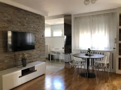 a living room with a table and a tv on a brick wall at Apartment Arena Lux in Fontana