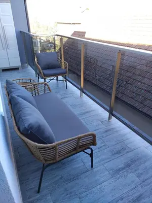 a porch with a couch and a chair on a balcony at BellaCasa AirportStudio in Surčin
