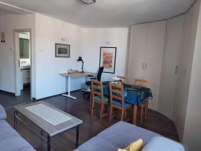 a living room with a table and chairs and a kitchen at Charming and stylish centrally located 50m2 in Belgrade