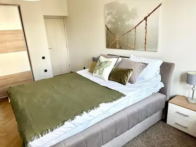 a bedroom with a bed with a green blanket on it at Dani City Center Apartment in Belgrade