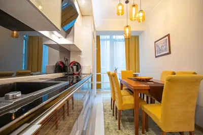 a kitchen and dining room with a wooden table and yellow chairs at Dani City Center Apartment in Belgrade