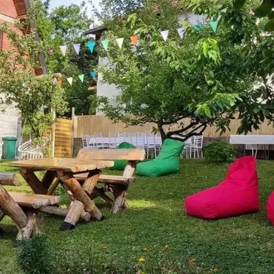 a picnic table with red and green cushions next to a tree at Kosmajski raj in Nemenikuće