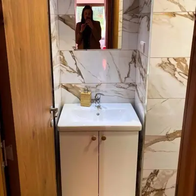 a woman taking a picture of a sink in a bathroom at Kosmajski raj in Nemenikuće