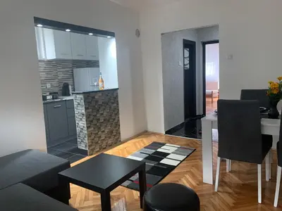 a living room with a table and a kitchen at Lana in Arandjelovac