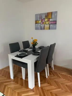 a white dining room table with black chairs and a painting at Lana in Arandjelovac