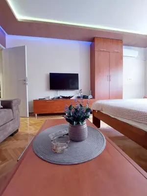 a living room with a bed and a table with flowers at Cuca Apartments in Belgrade