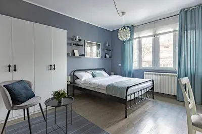 a bedroom with blue walls and a bed and a chair at Indigo Apartment in Belgrade